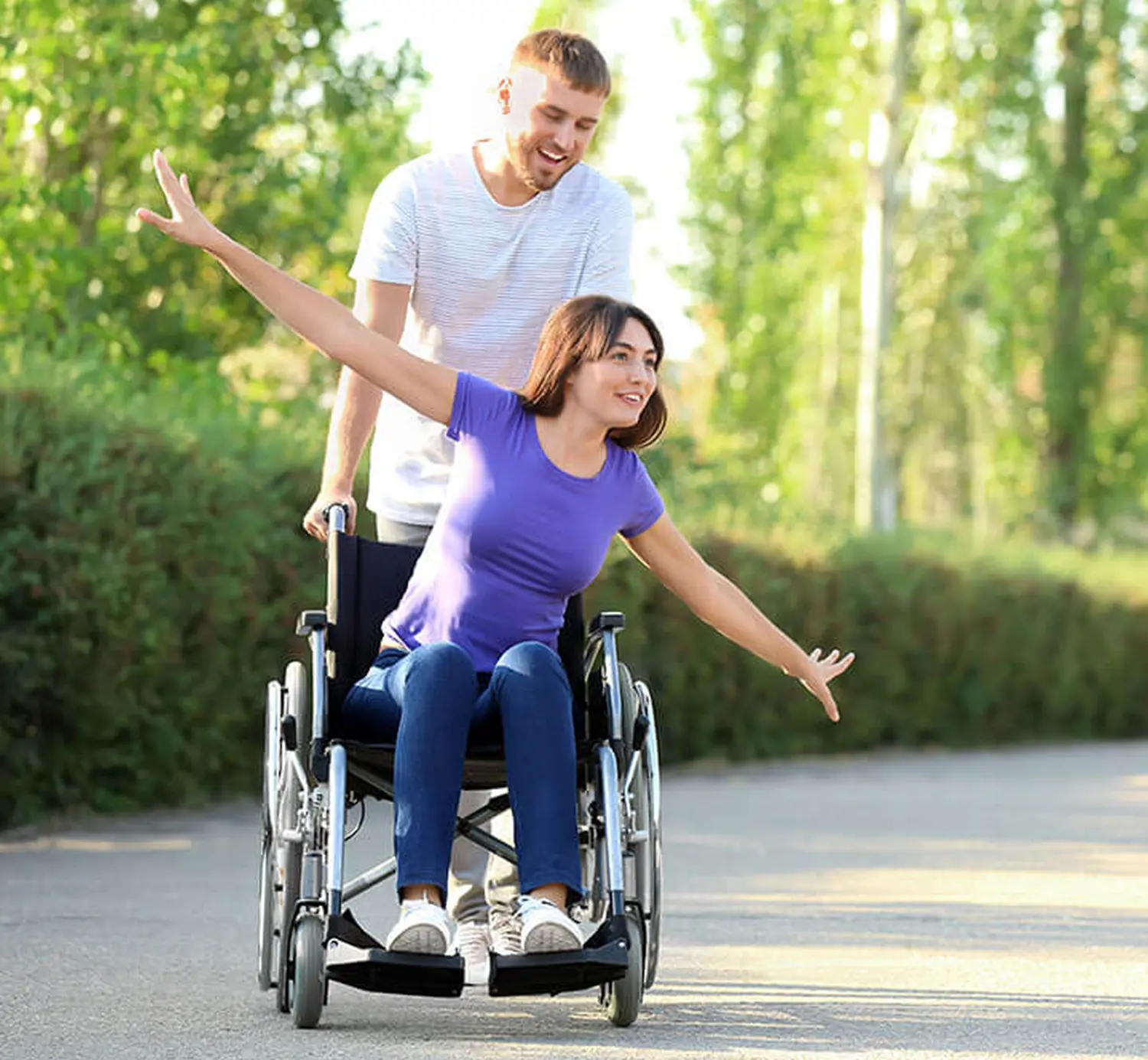 Pflegekreuz GmbH – Paar im Freien, Frau im Rollstuhl und Mann, der ihn stützt