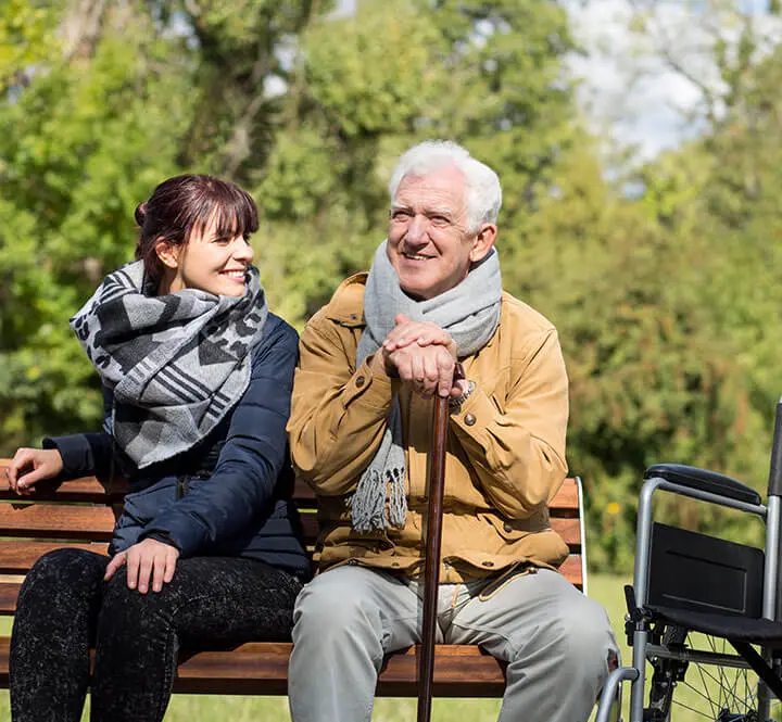 Pflegekreuz GmbH – Krankenschwester sitzt bei Seniorin